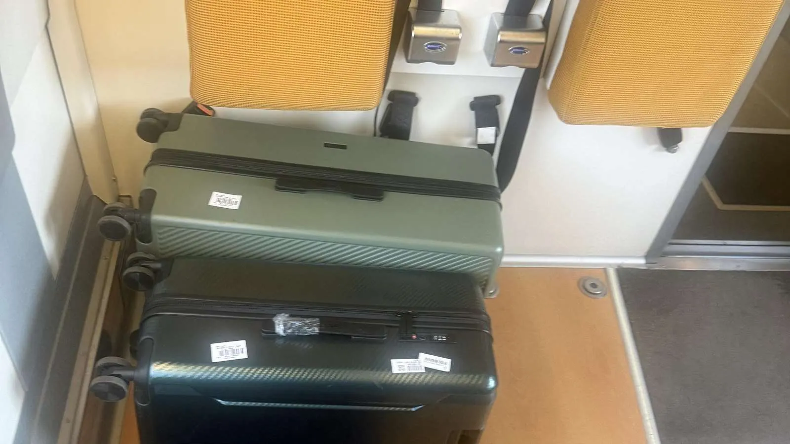 Three large suitcases stacked in the open luggage bay behind the last row of a Renfe AVE carriage