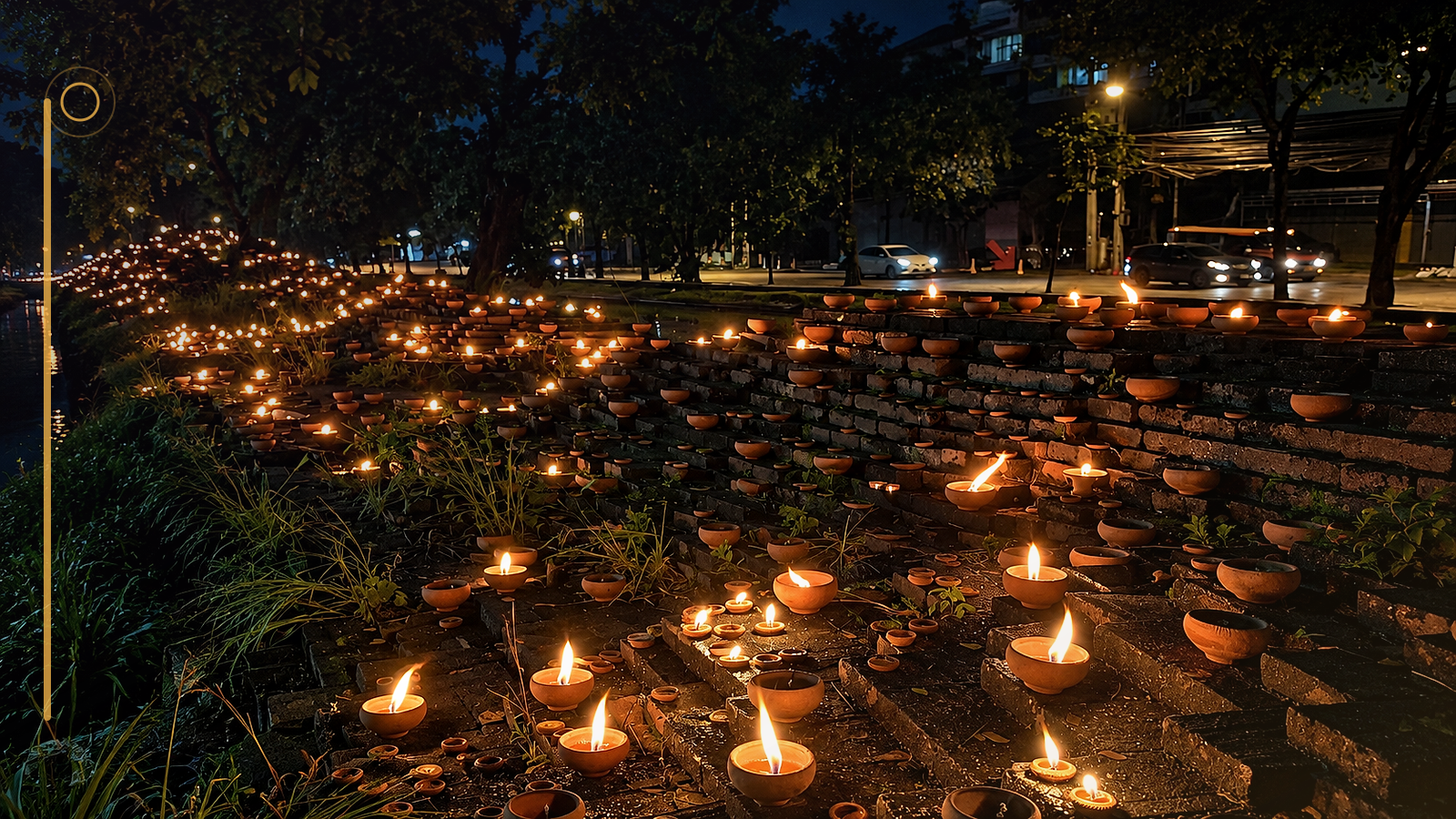 Terracotta candles line a canal-side wall during a night celebration in Chiang Mai